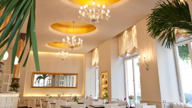 A restaurant with round tables, white chairs, and chandeliers. - The Heidelberg Exzellenz Hotel (Heidelberg)