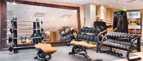Une salle de sport équipée de matériel de musculation, de bancs et d’un miroir.