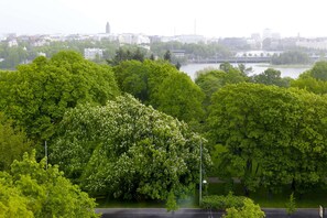 A park with dense green trees and a river in the background. - Scandic Park Helsinki (Helsinki)