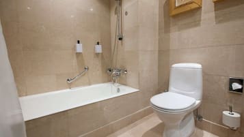 A modern bathroom with a bathtub, toilet, and hand dryer.
