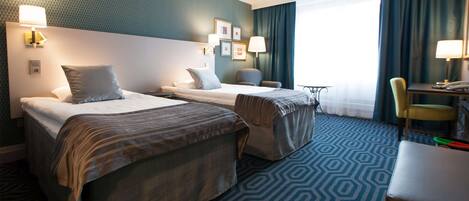 Una habitación de hotel con dos camas, un escritorio, una silla y una mesita.