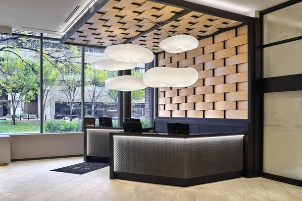 Una zona de recepción moderna con un muro de madera, ventanas amplias y un mostrador de recepción.