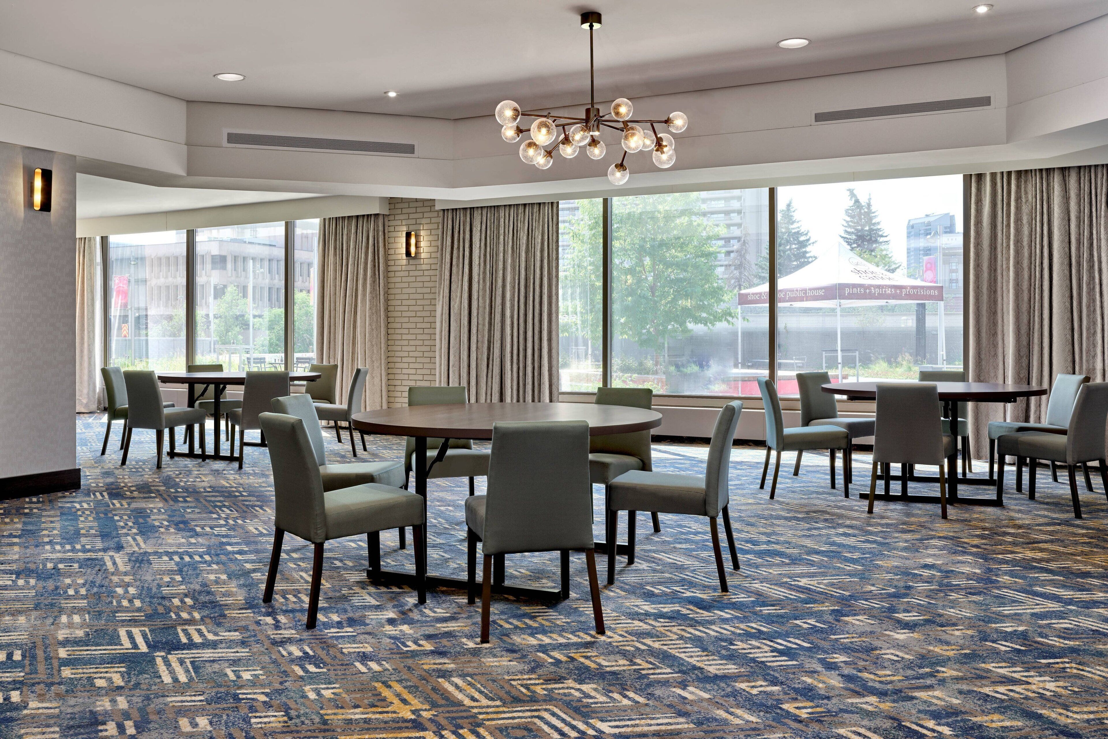 A conference room with a large round table, multiple chairs, and a patterned carpet.