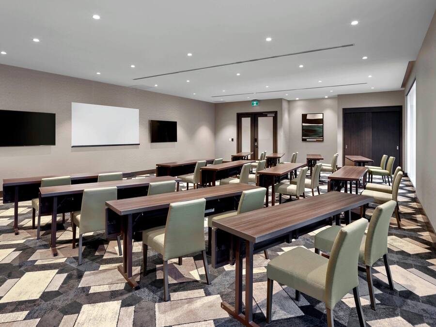 A conference room with multiple tables and chairs, a large whiteboard, and a television screen.