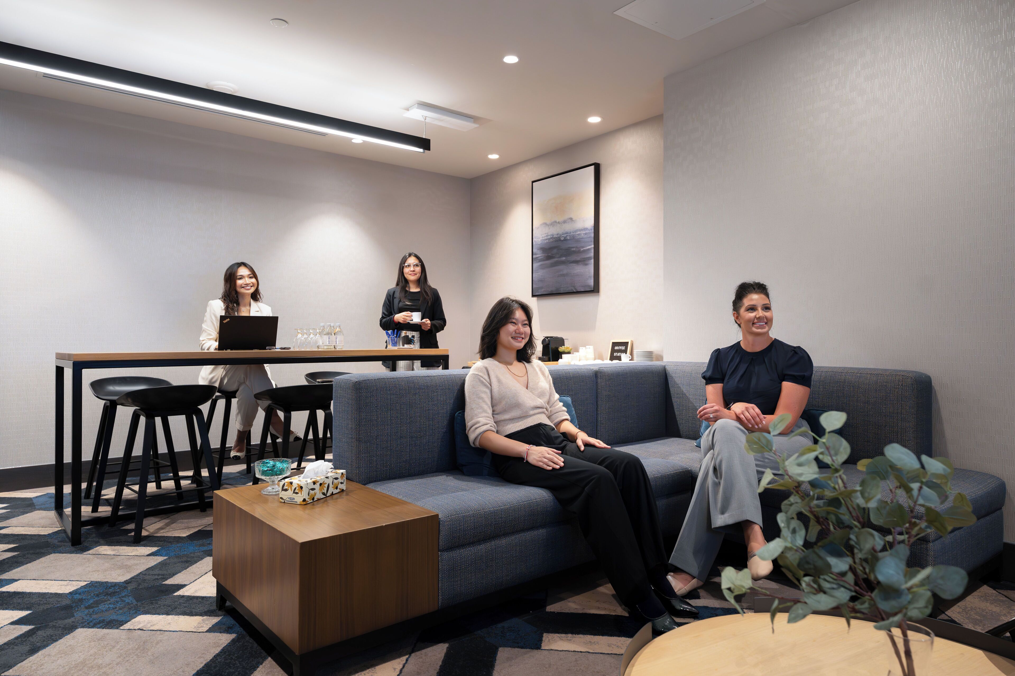 A modern lounge area with a sofa, a coffee table, and a bar area with stools.