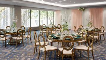 Comedor formal con mesas redondas, sillas doradas y una alfombra estampada.