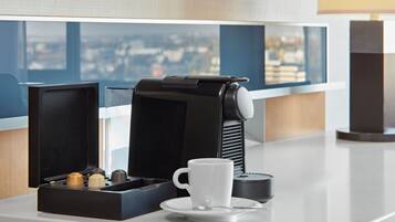 A coffee machine with a cup and saucer on a counter, with a window view in the background.