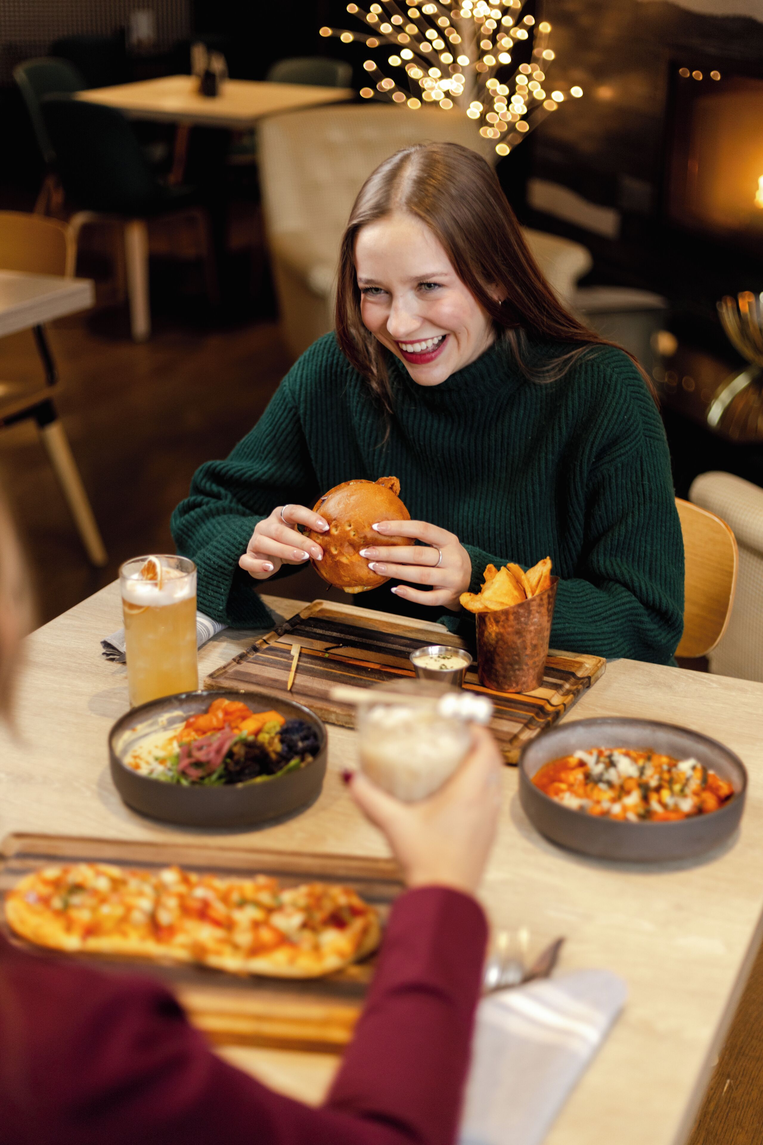 A dining table with a variety of dishes, including pizza, salad, and a burger.