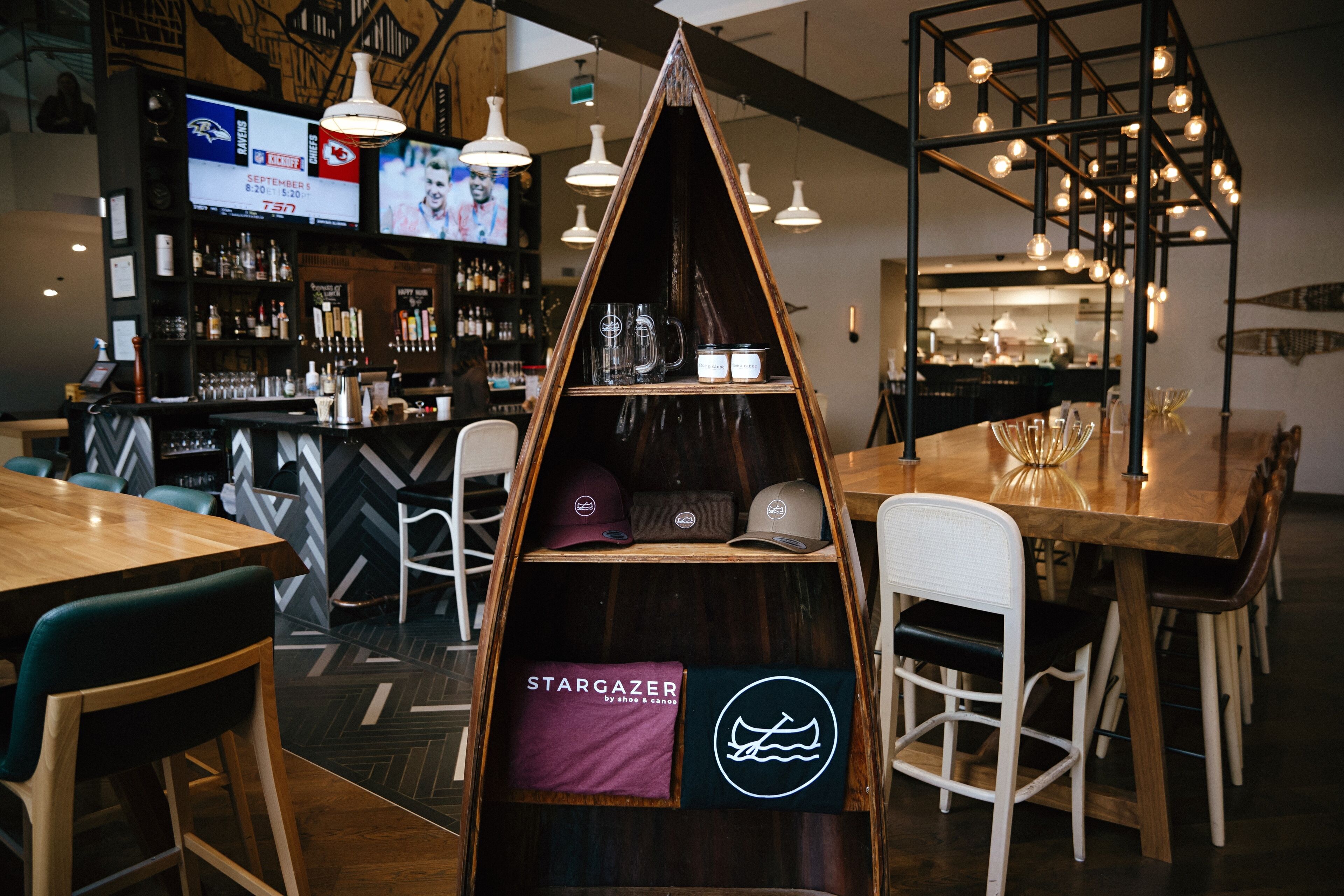 A bar area with wooden furniture, a counter with bottles, and a TV screen displaying sports.
