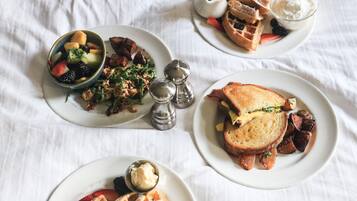 A table with various breakfast items including waffles, toast, and fruit.