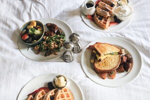 A table with various breakfast items including waffles, toast, and fruit.