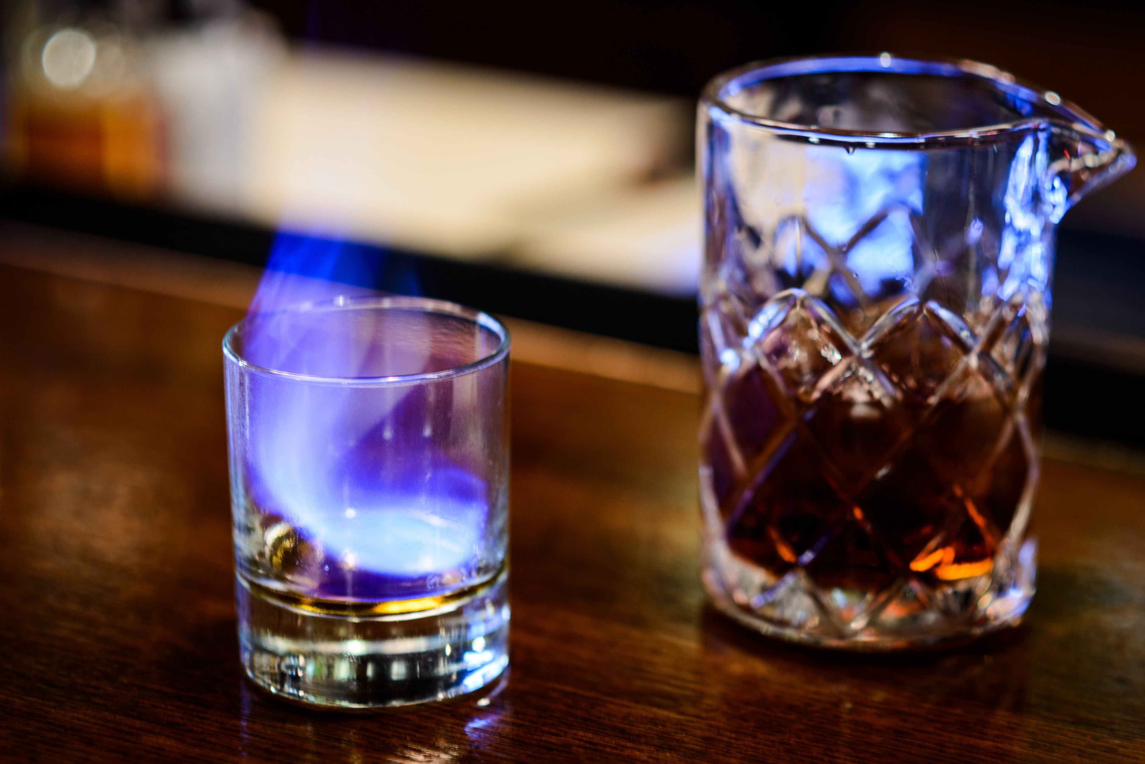 Un vaso corto de vidrio transparente y una jarra de cristal sobre una superficie de madera.