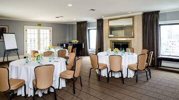 A conference room with round tables, chairs, and a piano.