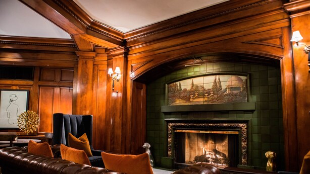 A cozy lounge area with a leather sofa, a fireplace, and wooden paneling. - Hotel Sorrento (Seattle)