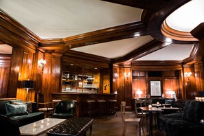 A bar area with wooden paneling, bar stools, and a bar counter.