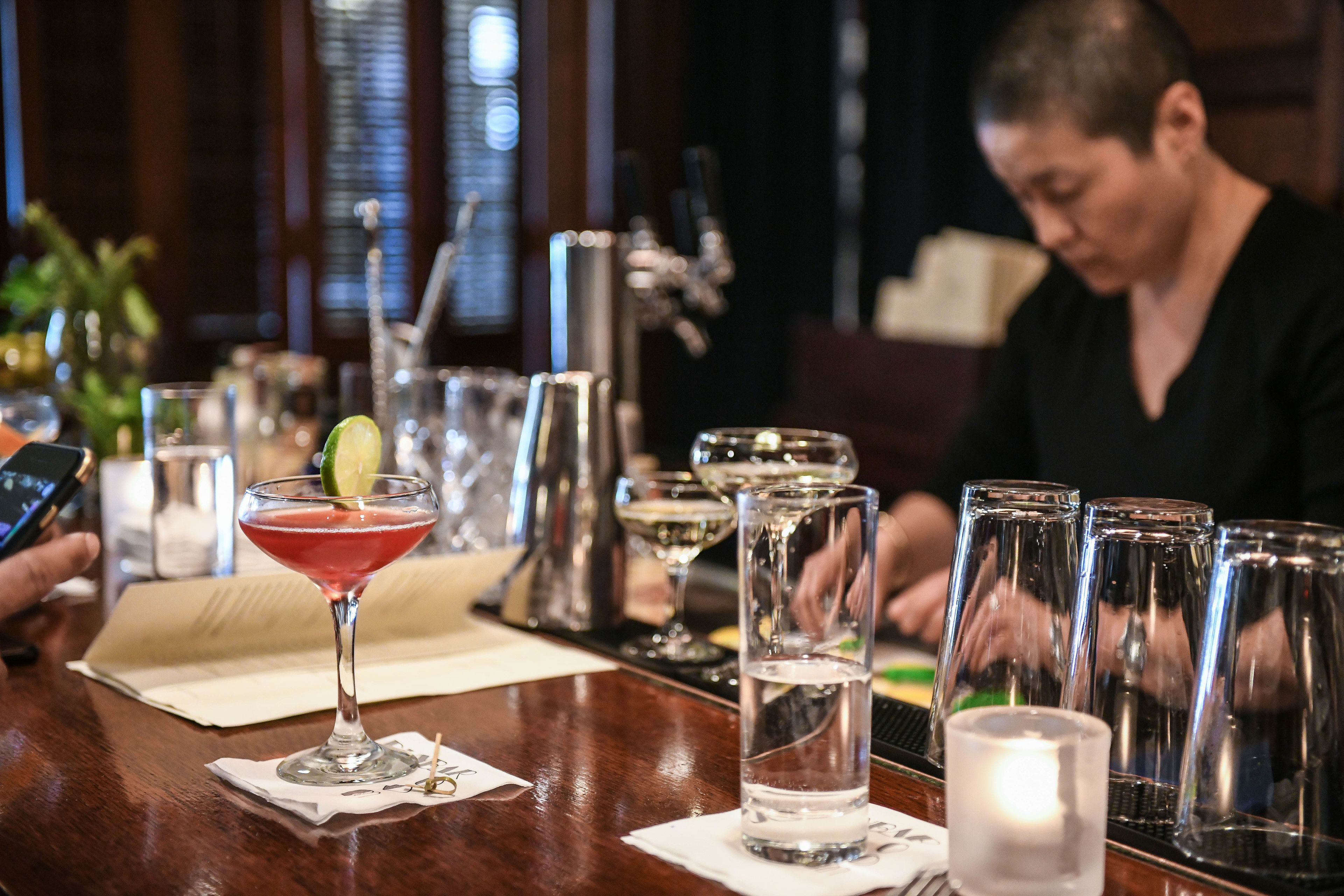 A bar area with a cocktail glass, water glasses, and a candle on the counter.