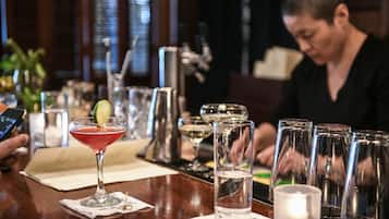 A bar area with a cocktail glass, water glasses, and a candle on the counter.