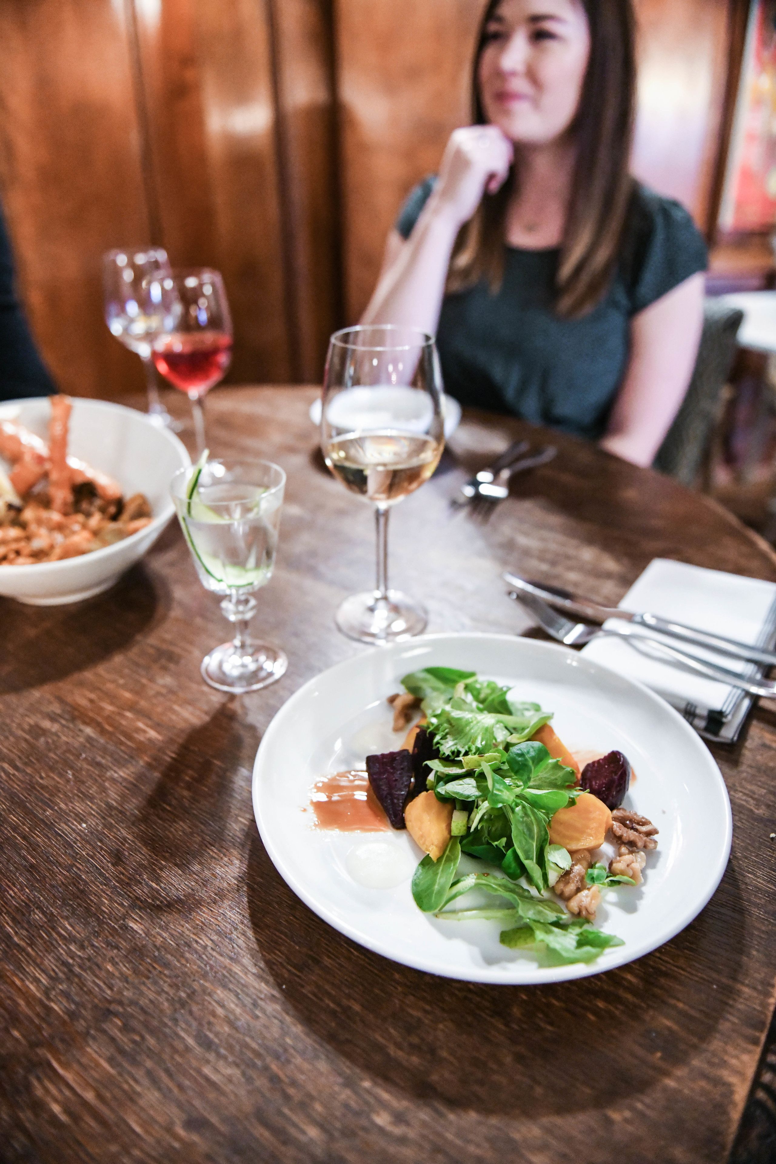 Una mesa de comedor con un plato de comida, copas de vino y cubiertos.