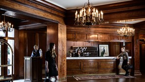 A lobby with wooden paneling, chandeliers, a reception desk, and a check-in counter. - Hotel Sorrento (Seattle)