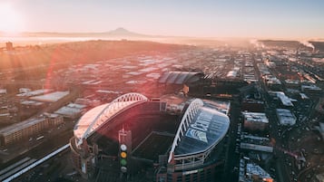 Un grand stade doté d’un toit incurvé, entouré d’infrastructures urbaines et avec une montagne visible au loin.