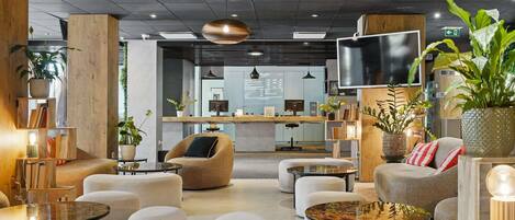 A modern lounge area with seating, a reception desk, and a television.