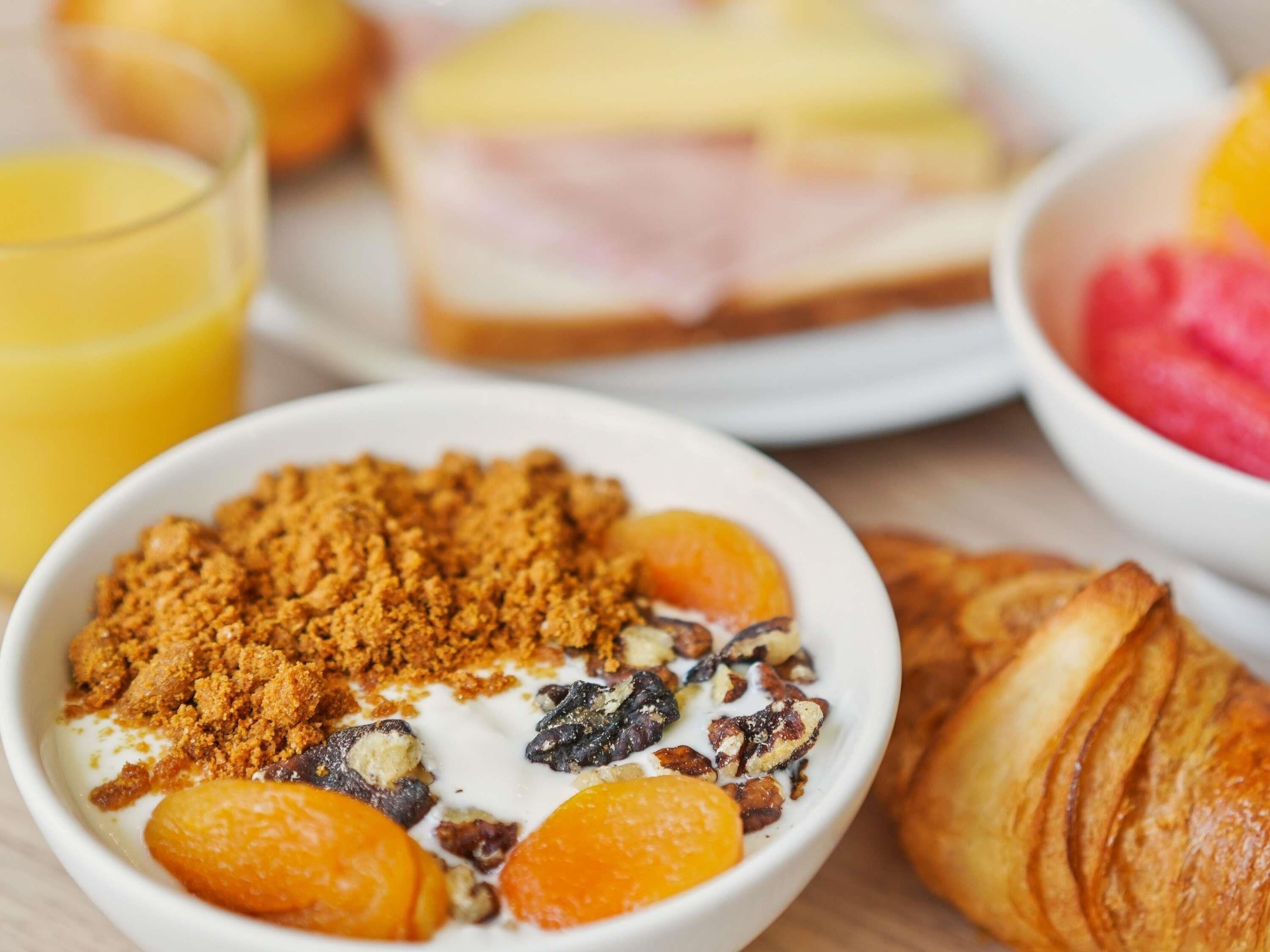 A breakfast setting with a bowl of cereal, a croissant, and a glass of orange juice.
