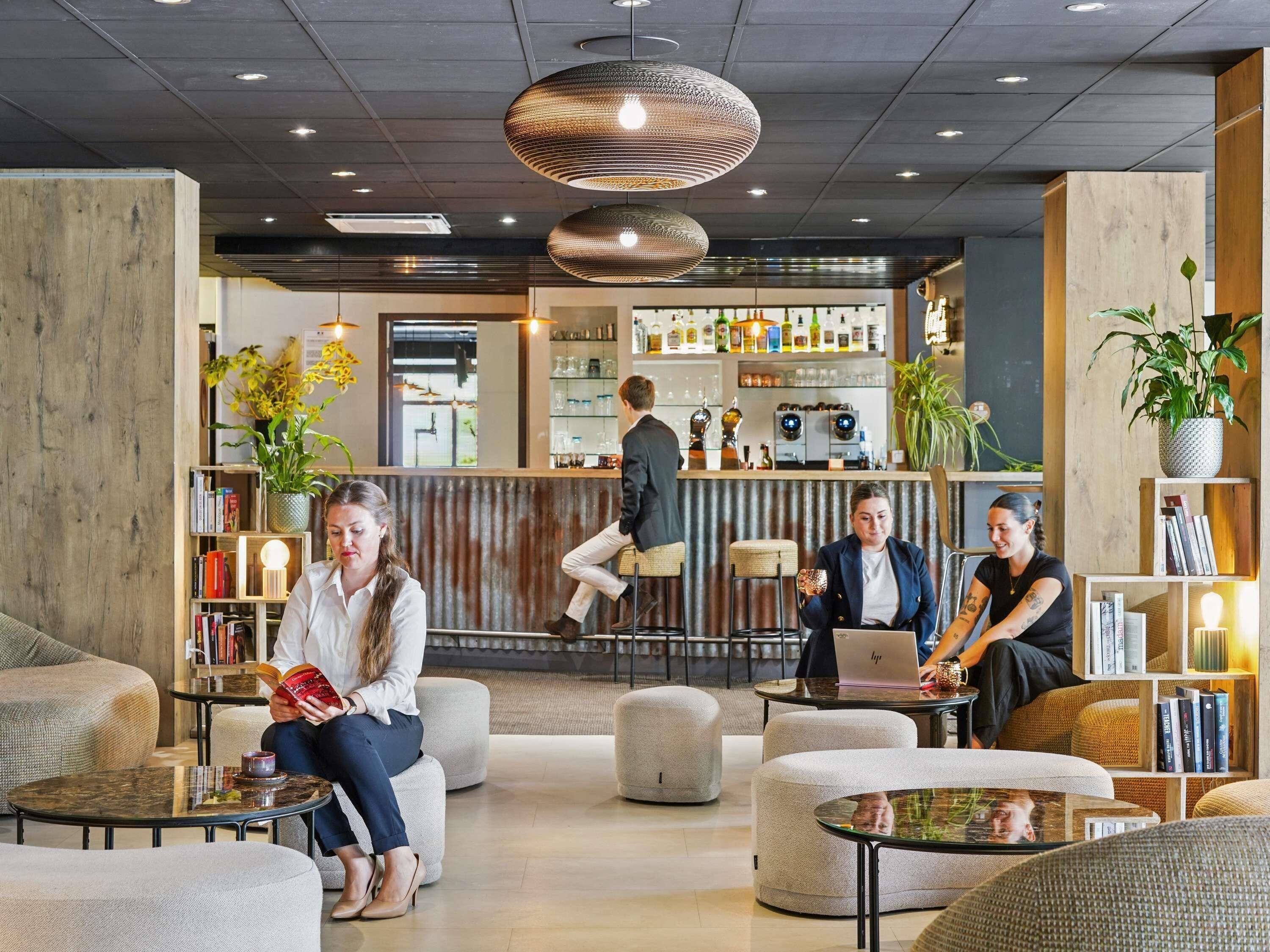 A modern lobby with seating areas, a bar, and a reception desk.