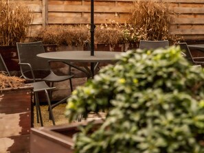 Enjoy an outdoor space with a round table and six chairs, surrounded by lush greenery and a wooden fence.