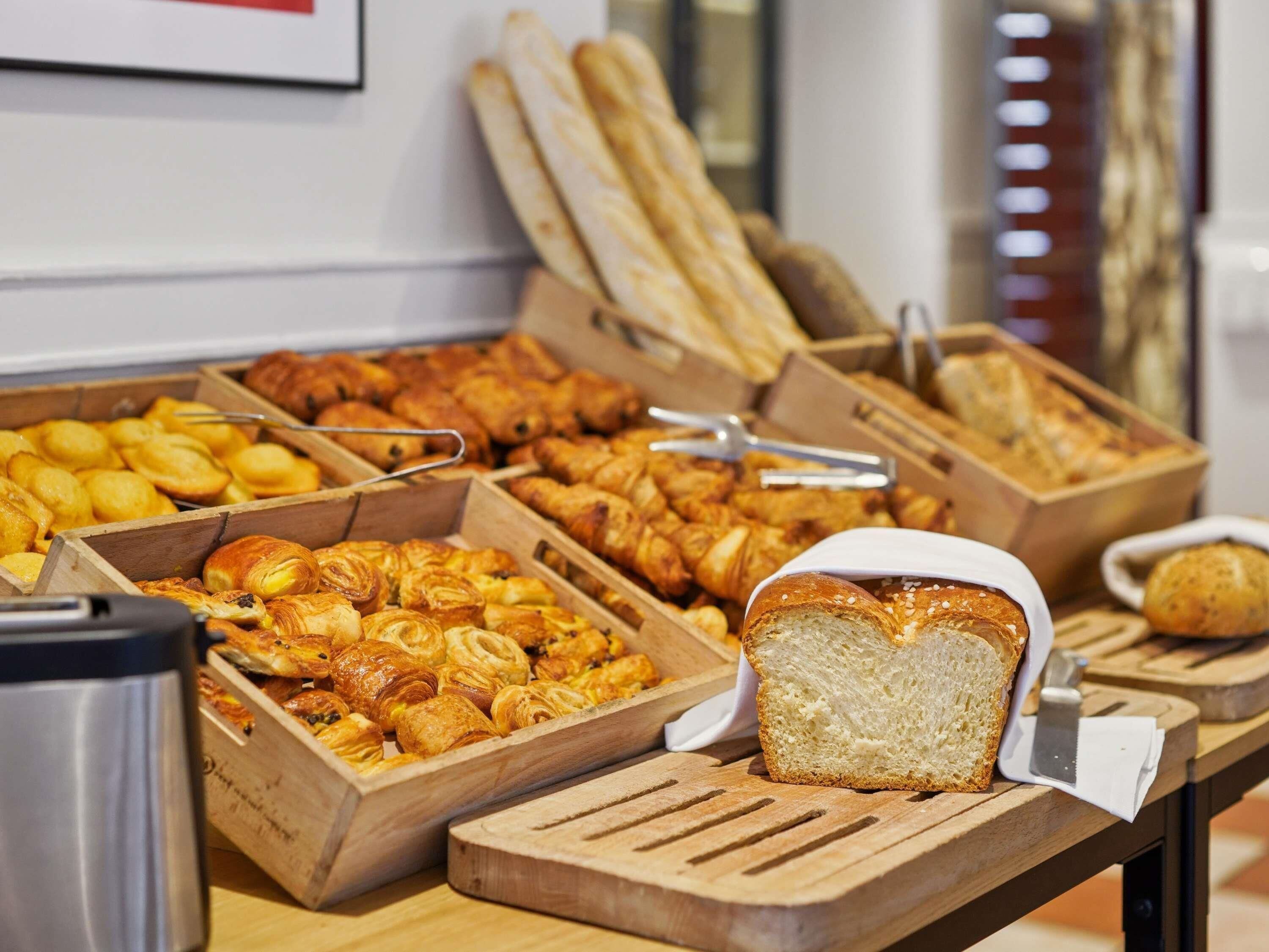 Un bufé con diversas opciones de panadería, incluyendo pan, pasteles y cruasanes.