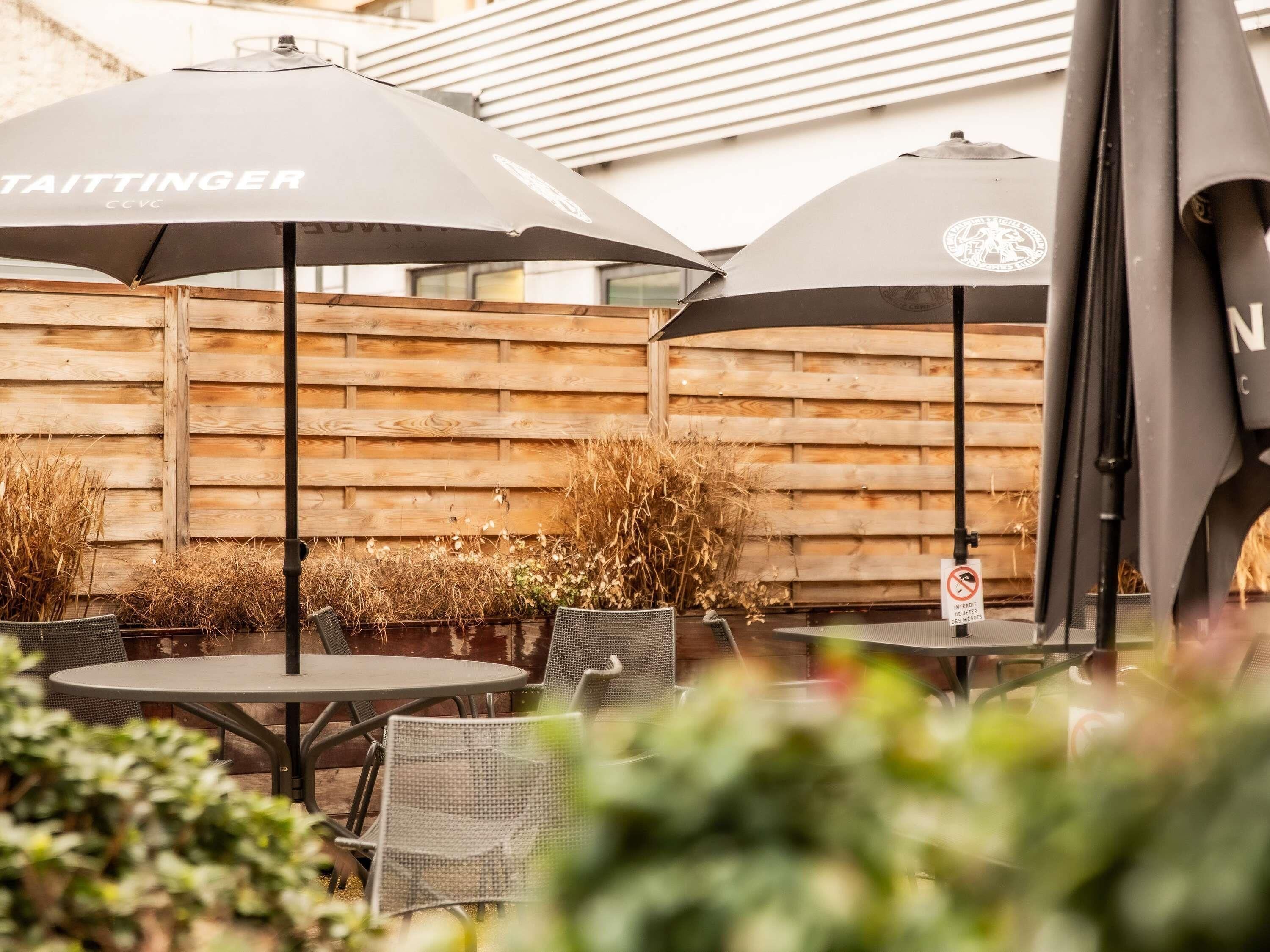 Outdoor seating with umbrellas, a wooden fence, and a sign indicating no smoking.