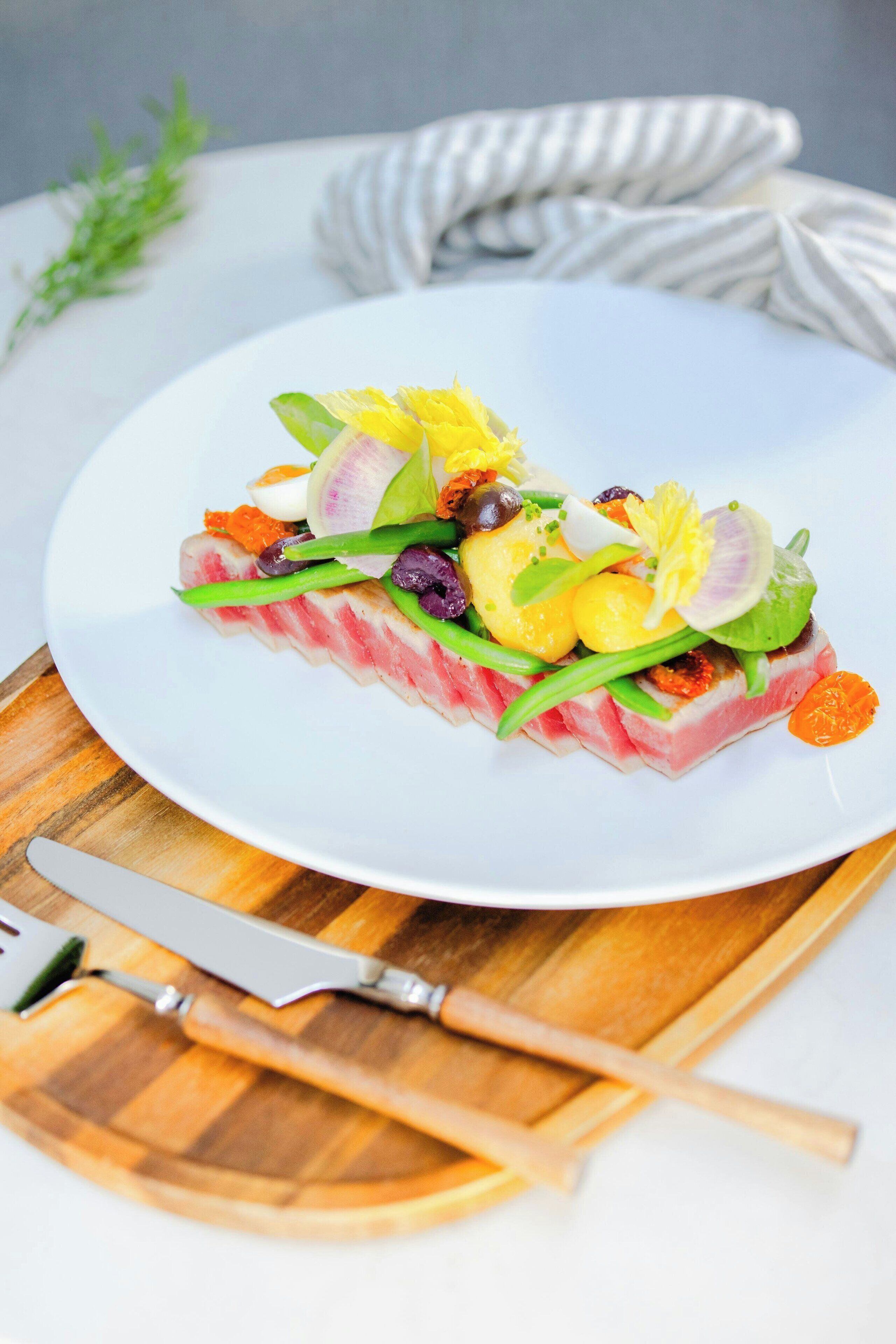 Un plato blanco con un plato de mariscos, un cuchillo y una tabla de madera sobre una mesa.