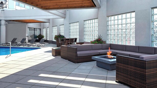 Un área lounge moderna al aire libre con piscina, asientos y una chimenea.