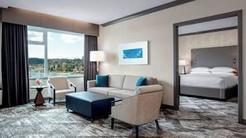 A hotel room with a sofa, armchair, ottoman, and a bed.