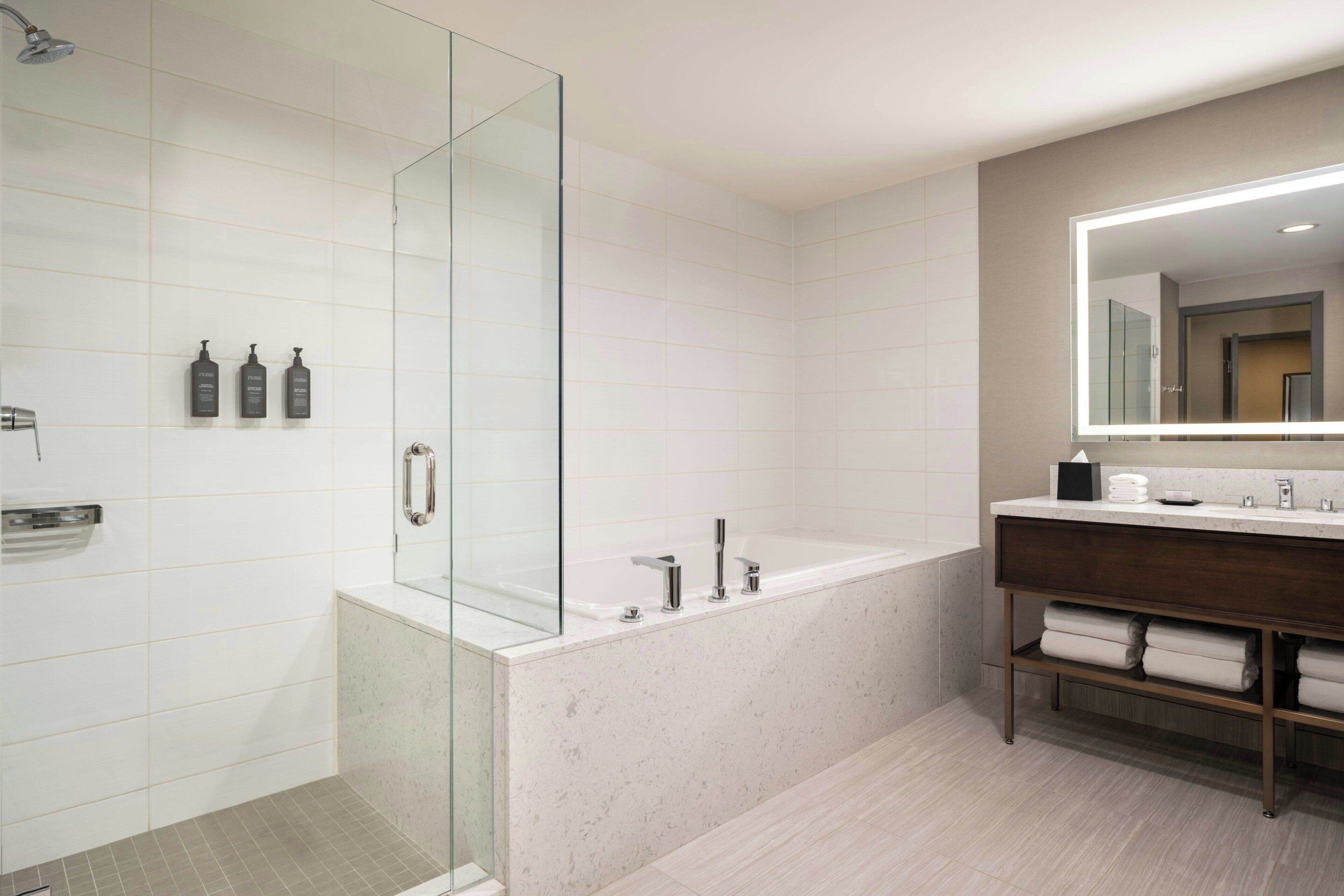 Un baño moderno con cabina de ducha de vidrio, bañera independiente y tocador con espejo.