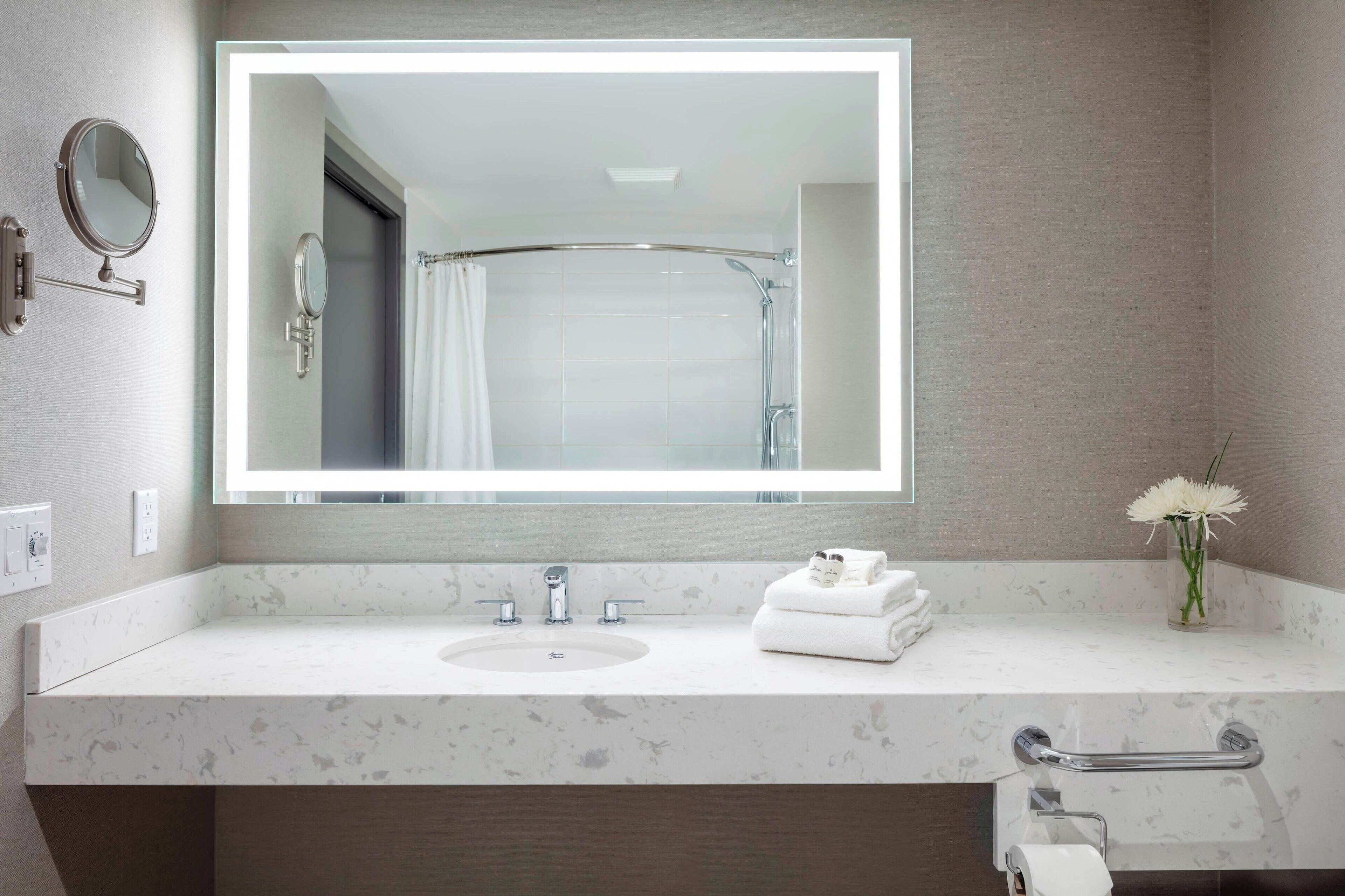 Un bagno moderno con un grande specchio, un lavandino, un portascopevoli e una tenda per la doccia.