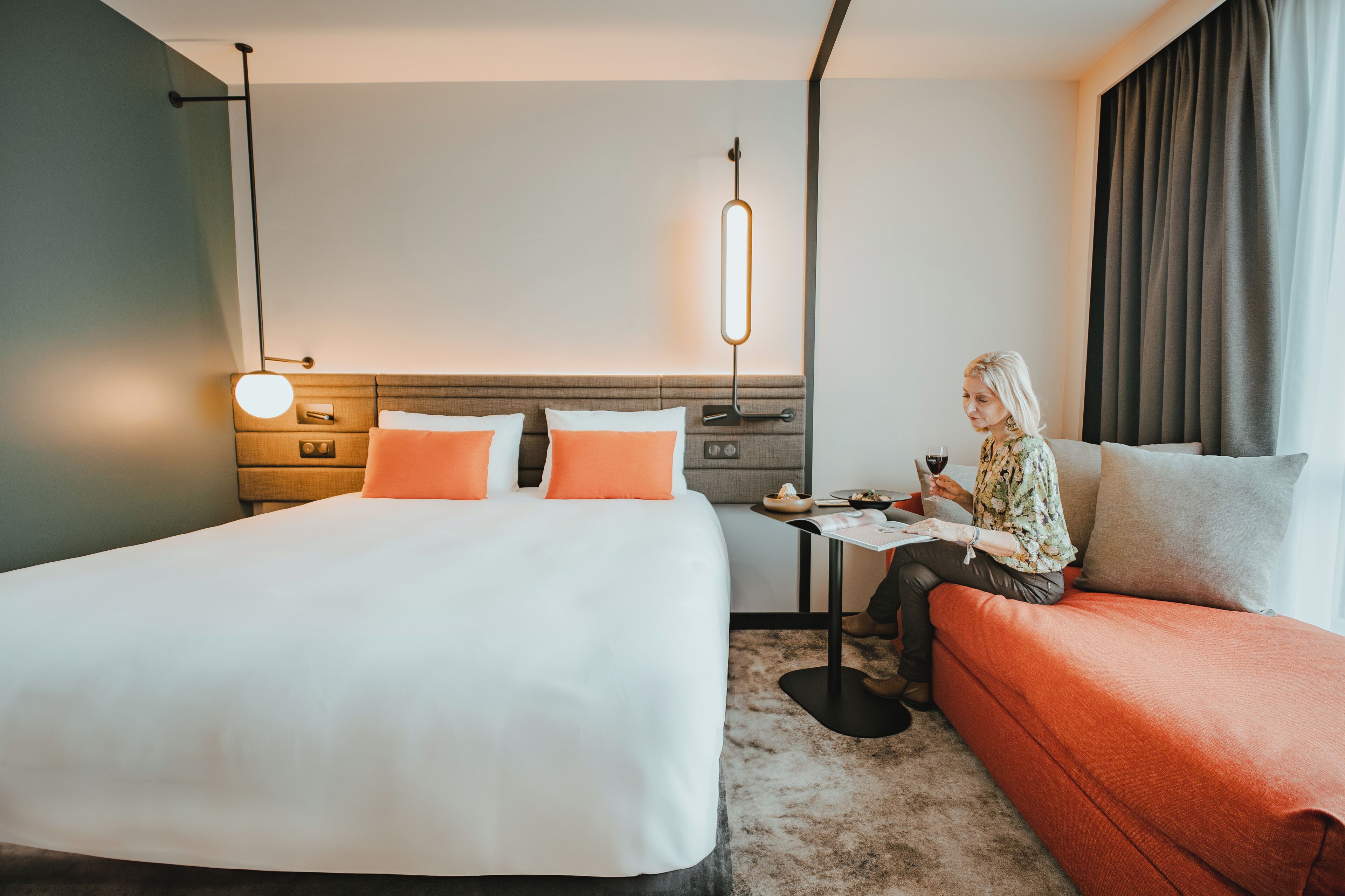 A hotel room with a large bed, a small table, and a sofa.