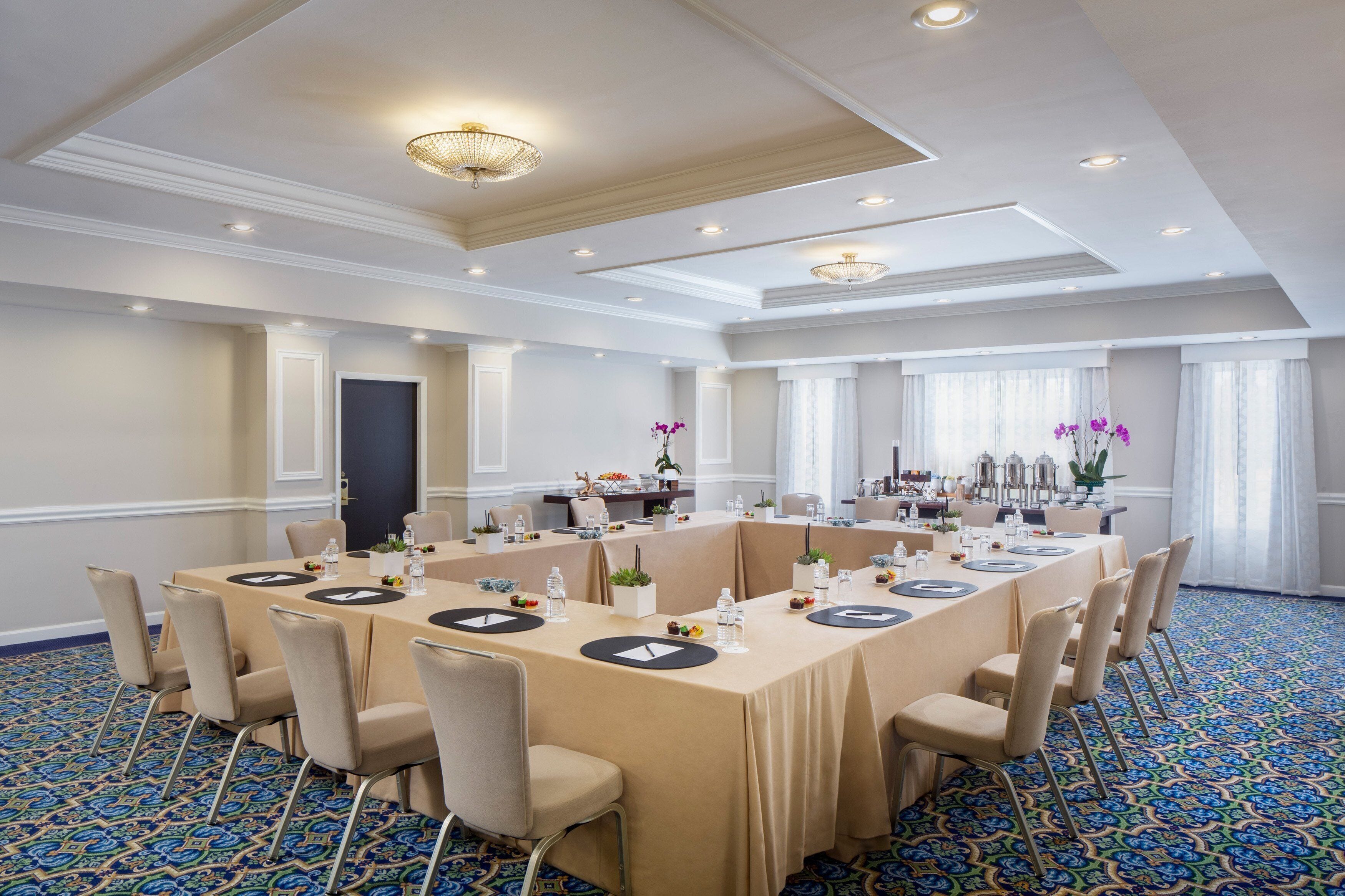 A conference room with a long table, beige chairs, and a patterned carpet.