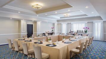 A conference room with a long table, beige chairs, and a patterned carpet.
