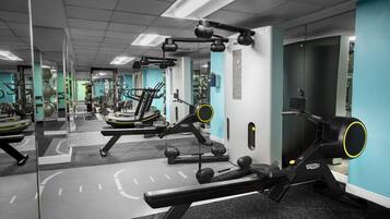 Un gimnasio con equipamiento de ejercicio, paredes espejadas y un diseño moderno y limpio.
