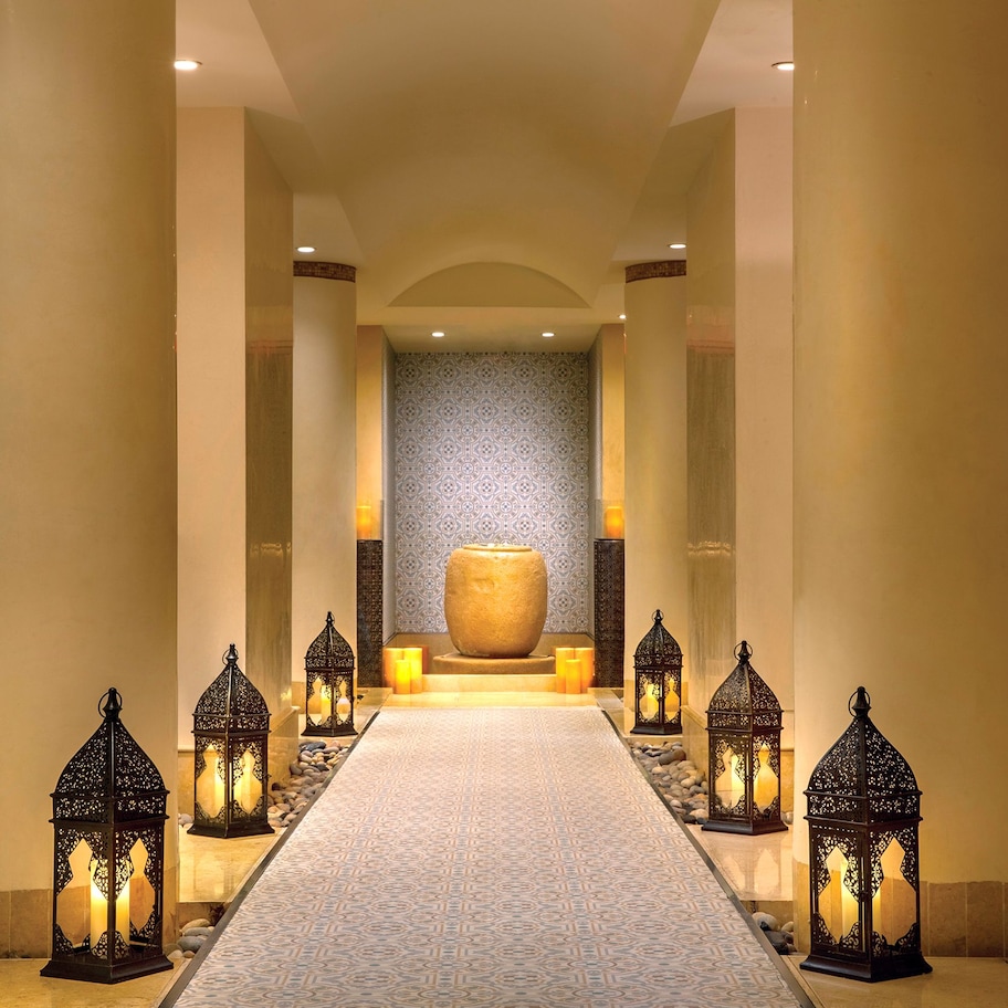 A hallway with a patterned carpet, a large central vase, and decorative lanterns.