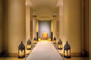 A hallway with a patterned carpet, a large central vase, and decorative lanterns.