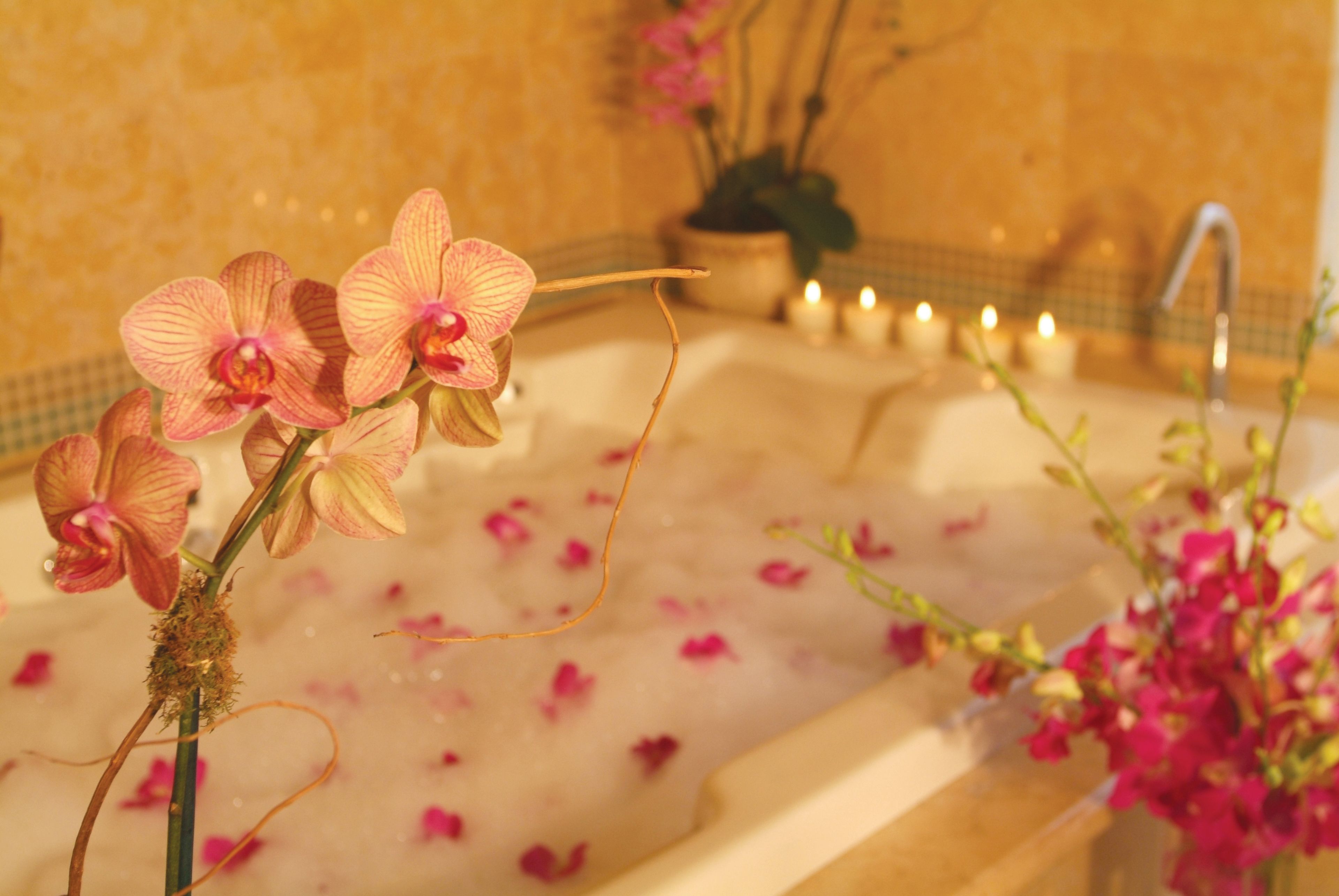 Una bañera con orquídeas rosas y velas.