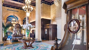 Un vestíbulo imponente con una gran araña, columnas ornamentadas y un piso con diseño.