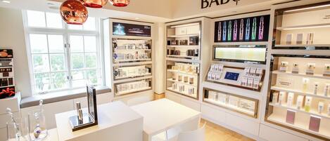 A clean, well-lit store with shelves of products and a white table with chairs.
