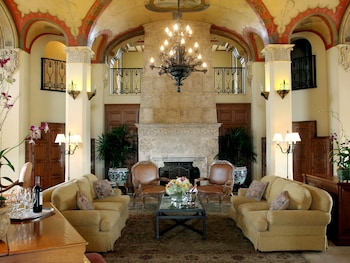 A grand dining hall with ornate columns, a harp, and a chandelier. Tables are set with fine china and floral arrangements. at Biltmore Hotel - Miami - Coral Gables