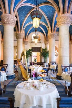 A banquet hall with rows of tables and chairs, a stage with a presentation screen, and a chandelier. at Biltmore Hotel - Miami - Coral Gables