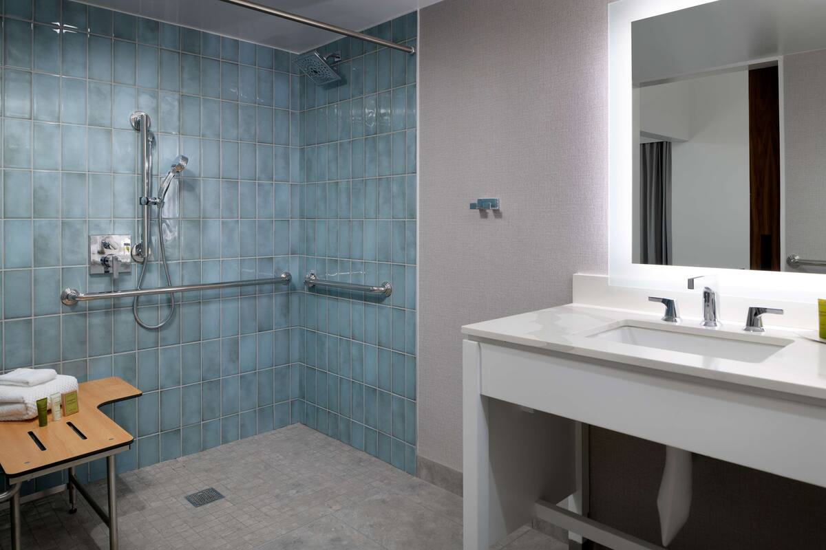 Une salle de bain avec une douche, un lavabo et un miroir.