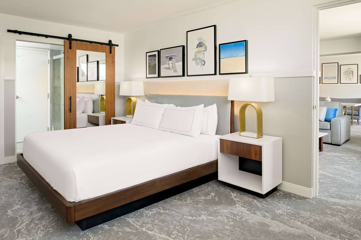 Une chambre d’hôtel moderne avec un grand lit, des tables de chevet et un placard à portes coulissantes.