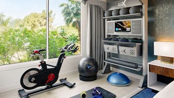 A modern gym with a stationary bike, exercise balls, and a rowing machine.