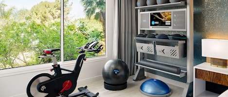 Un gimnasio moderno con una bicicleta estática, pelotas de ejercicio y una máquina de remo.